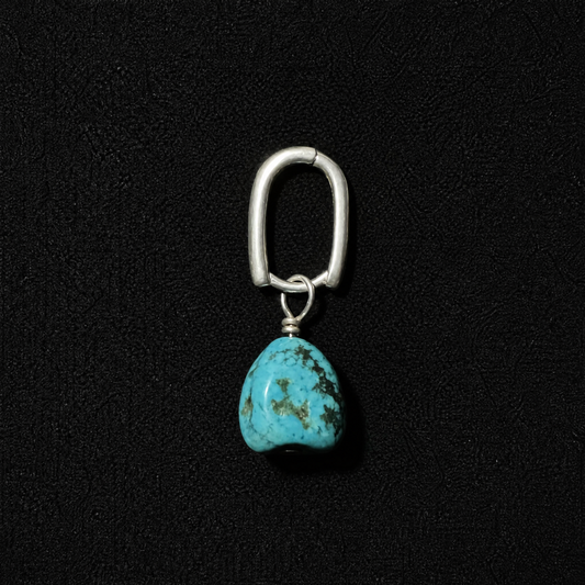 Unisex model wearing a 925 sterling silver irregular dangle earring featuring a natural raw turquoise nugget and silver tassel