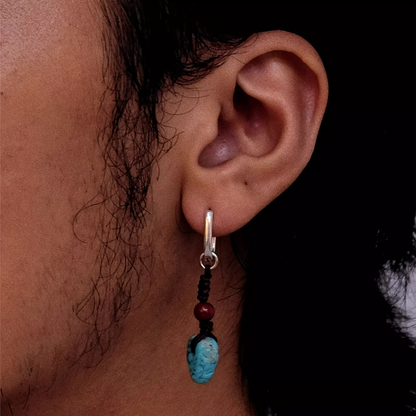 Silver hoop earring with hand-knotted cord, red bead, and turquoise dangle.
