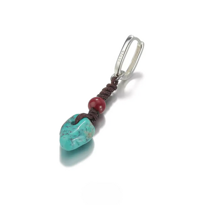 Silver hoop earring with hand-knotted cord, red bead, and turquoise stone.