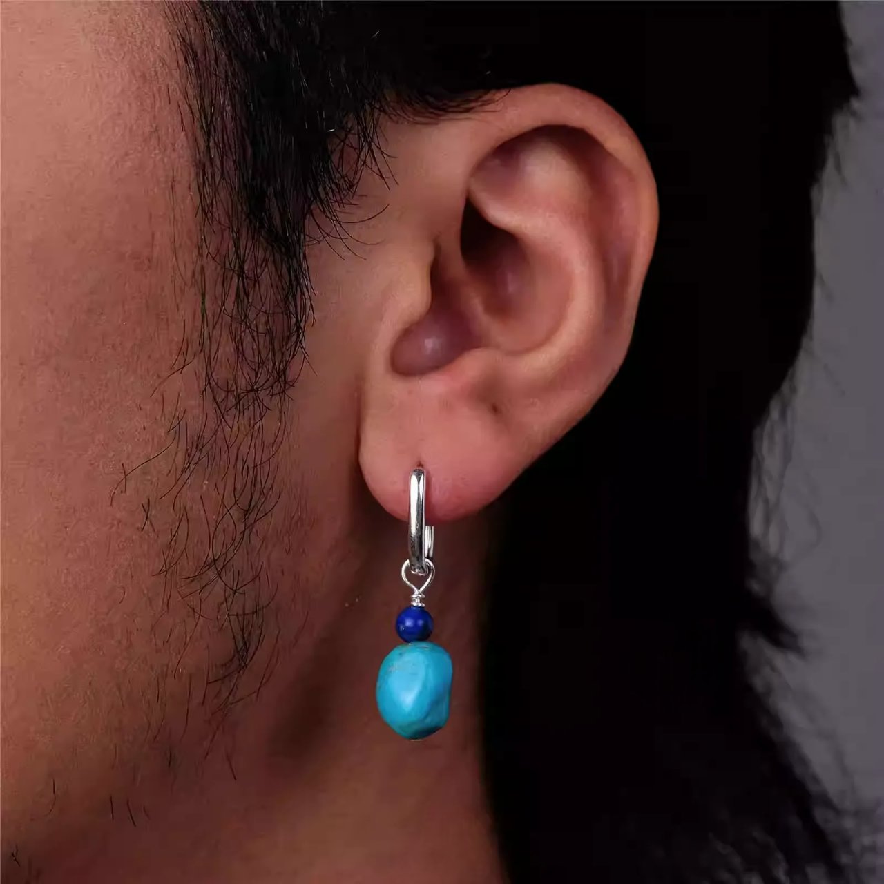 Silver hoop earring with blue lapis lazuli and raw turquoise drop on an ear.