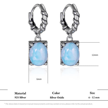 Two oxidized silver hoop earrings with light blue oval larimar drop stones.