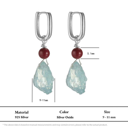 Silver dangle earrings with red beads and raw light blue aquamarine stones.