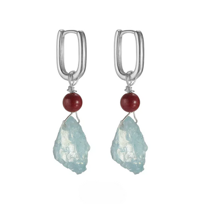 Pair of silver hoop earrings with red cinnabar beads and raw aquamarine stones.