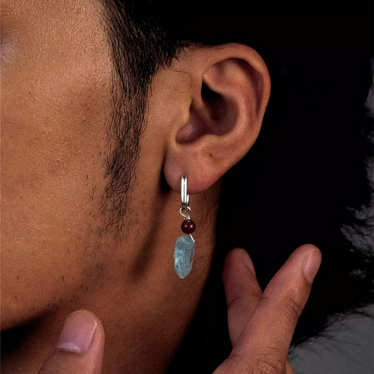 Silver hoop earring with a red bead and a raw light blue aquamarine stone dangle.