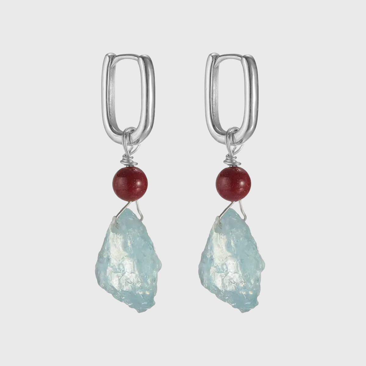 Silver hoop earrings with red beads and raw light blue aquamarine stones.