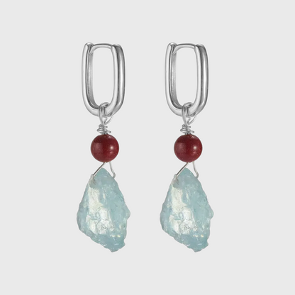 Silver hoop earrings with red beads and raw light blue aquamarine stones.