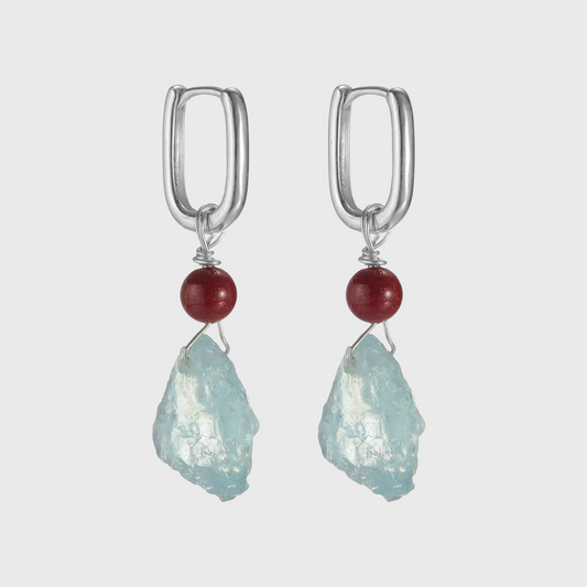 Silver hoop earrings with red beads and raw light blue aquamarine stones.