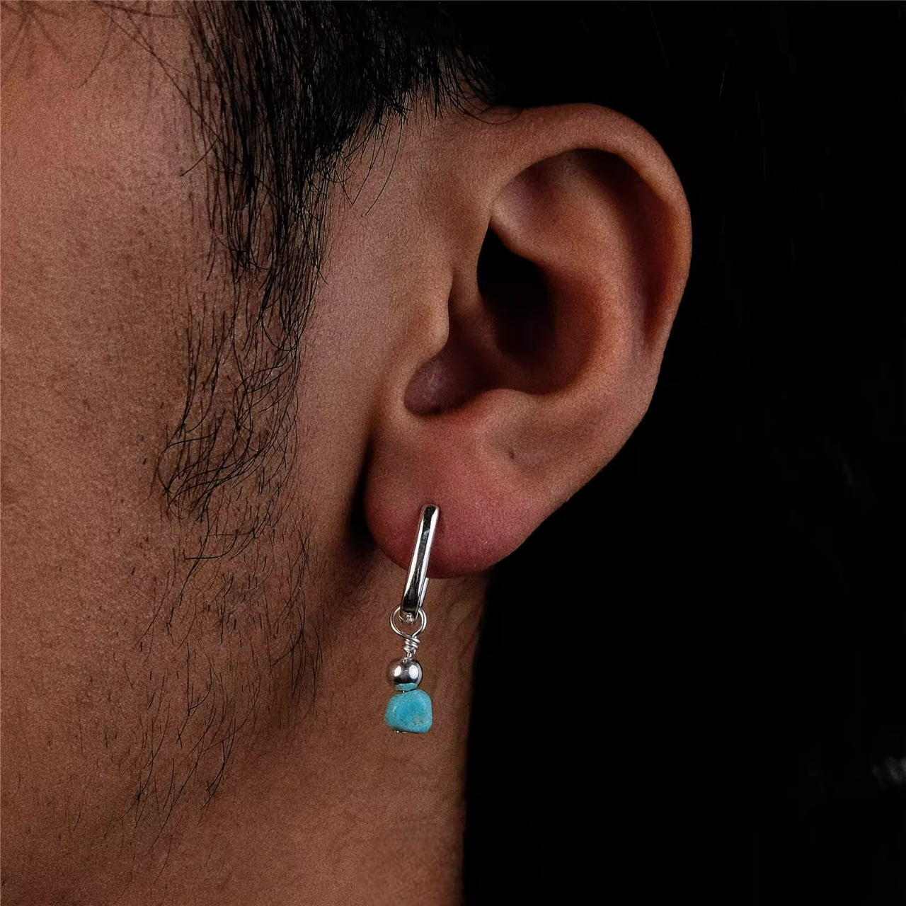 A silver rectangular huggie earring with a raw turquoise nugget drop.
