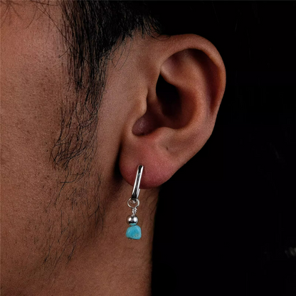 A silver rectangular huggie earring with a raw turquoise nugget drop.