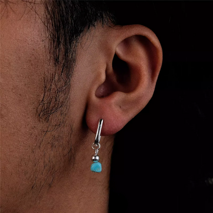 Silver rectangular huggie earring with a raw turquoise nugget drop on an ear.