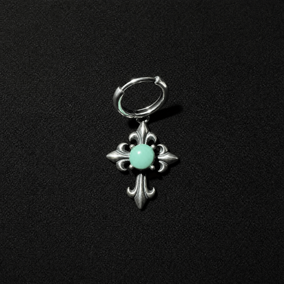 Unisex gothic punk S925 silver huggie earrings featuring a turquoise cross dangle, resting on a textured dark stone surface